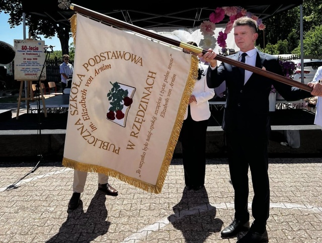 Dyrektor Robert Mazur ze Sztandarem Szkoły. Fot. ze zbiorów Publicznej Szkoły Podstawowej w Rzędzinach Elizabeth von Arnim wróciła do Rzędzin. Nowa patronka Publicznej Szkoły Podstawowej [POSŁUCHAJ]