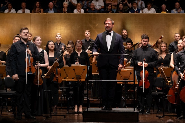 Przemysław Neumann – dyrygent i Orkiestra Symfoniczna ILYO 2024 przyjmują gorące brawa publiczności. Fot. Piotr Makowski Finał 12. International Lutosławski Youth Orchestra w Złotej Sali Filharmonii [ZDJĘCIA]