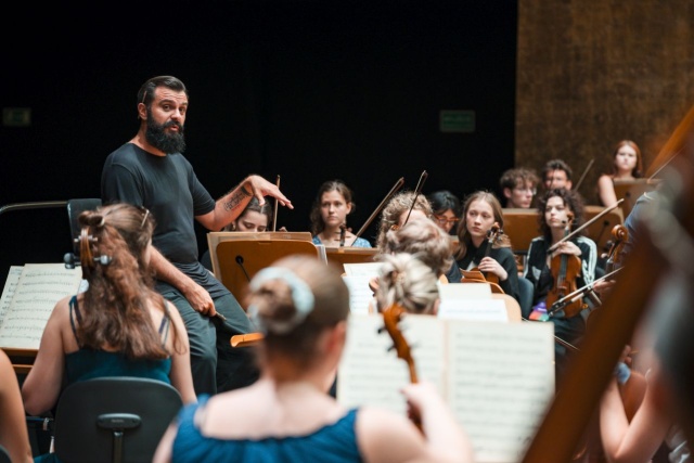 Mateusz Czarnowski – kompozytor, dyrygent, kierownik Działu Wydarzeń Edukacyjnych Filharmonii w Szczecinie na próbie Orkiestry ILYO 2025. Fot. Piotr Nykowski Finał ILYO 2025 w Złotej Sali Filharmonii [ZDJĘCIA]