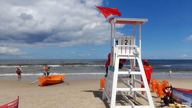 Czarne chmury nad i czerwona flaga na kąpielisku morskim w Świnoujściu. Warunki pogodowe nad Bałtykiem utrudniają morski kąpiele.