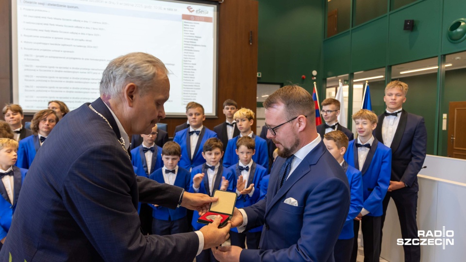 Kamil Szałata (od prawej) – dyrygent, dyrektor Szczecińskiego Chóru Chłopięcego „Słowiki” przyjmuje Medal z rąk Pawła Bartnika – przewodniczącego Rady Miasta Szczecin. Fot. Robert Stachnik [Radio Szczecin]