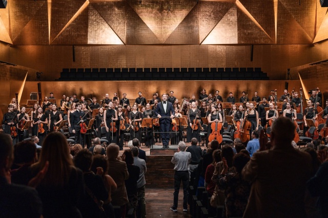 Maestro Przemysław Neumann przyjmuje owacyjne brawa publiczności z Internatiol Lutosławski Youth Orchestra. Fot. Piotr Nykowski Zofia Anna Olesik i orkiestra ILYO owacyjnie przyjęci w Złotej Sali Filharmonii [ZDJĘCIA]